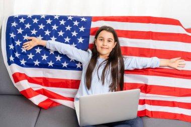 Çevrimiçi okul eğitimine dönelim. İngilizce konuşmak zor oluyor. Bilgisayarda ödev yapan bir çocuk. Öğrenci, dizüstü bilgisayarında Amerikan bayrağı üzerinde çalışıyor. Öğretmen uzaktan öğretiyor..