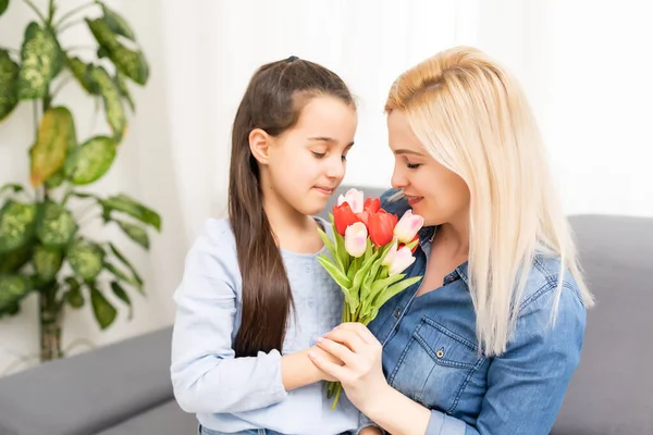 Happy mothers day. Child daughter congratulates moms and gives flowers tulips — Stock Photo, Image