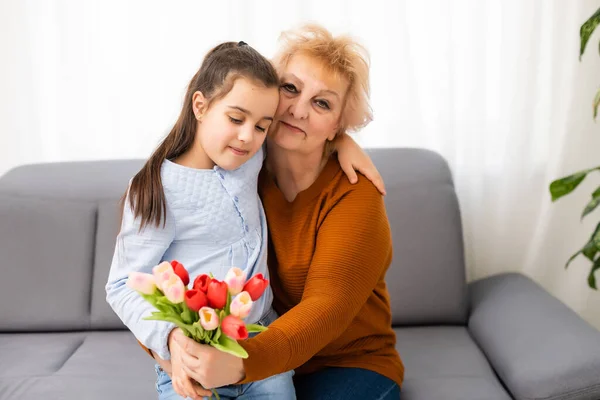 Menina visitando sua avó doente dando flores — Fotografia de Stock