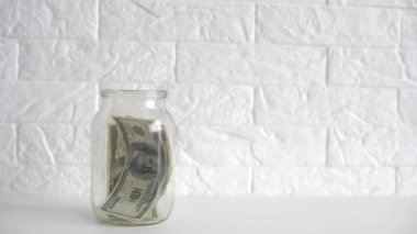 Cam kavanozdaki dolarlar. Erkeklerin kavanoza dolar koyduğu bir manzara. Evde para biriktirme kavramı.