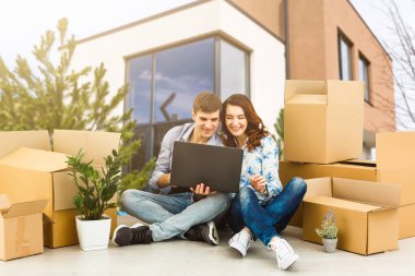 Arka planda yeni evleri olan ve gülümseyen mutlu bir çift.