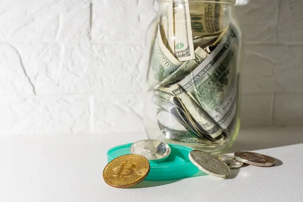 Bitcoin χάλκινο χρυσό νόμισμα σε γυάλινο βάζο σε λευκό φόντο. Ένα σετ κρυπτονομισμάτων με αληθινά δολάρια σε ένα γυάλινο βάζο. Ταμιευτήρια, επενδύσεις, έννοια χρηματοοικονομικού κινδύνου — Φωτογραφία Αρχείου