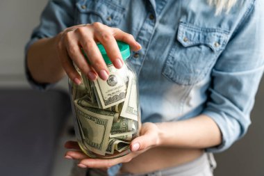 Kadın elinde Amerikan doları dolu şeffaf bir kavanoz tutuyor. Alışveriş konsepti