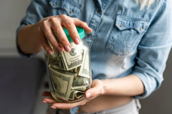 Kadın elinde Amerikan doları dolu şeffaf bir kavanoz tutuyor. Alışveriş konsepti — Stok fotoğraf