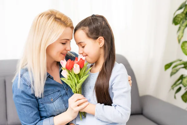 Child daughter congratulates mother and gives a bouquet of flowers tulips — Stock Photo, Image