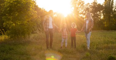 Mutlu aile: anne baba ve kız gün batımında doğada