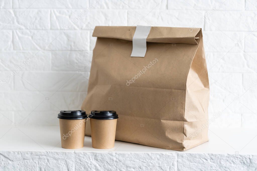 Fast food packaging set. Paper coffee cups in holder, food box, brown paper bag on the table