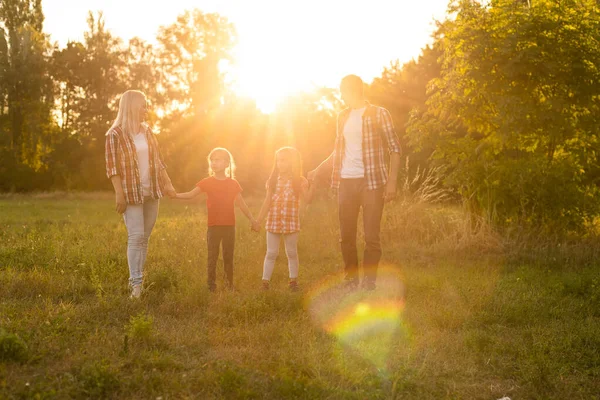 Família feliz andando no campo e olhando para o pôr do sol — Fotografia de Stock