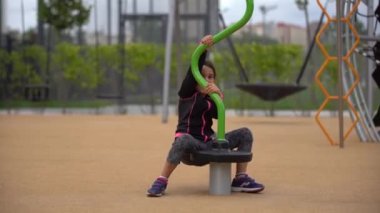 Çocuk parkında oynayan küçük kız. Mutlu çocuk oyun parkına tırmanıyor, salıncak ve bungee sürüyor, aktif bir yaşam tarzı.