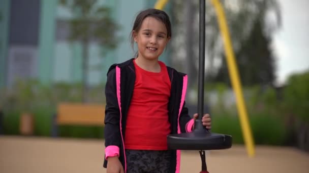 Meisje dat op de speelplaats speelt. Gelukkig kind klimmen op speeltuin net, paardrijden een schommel en bungee, actieve levensstijl — Stockvideo