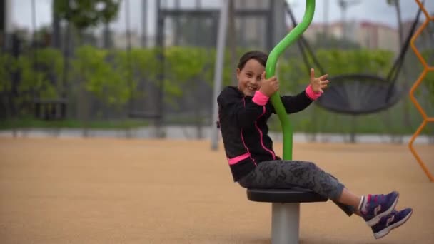 Holčička si hraje na hřišti. Happy child climbing up on playground net, riding a swing and bungee, active lifestyle — Stock video