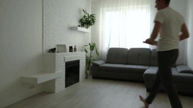 Genç adam evdeki duvarlara tuvaller asıyor.