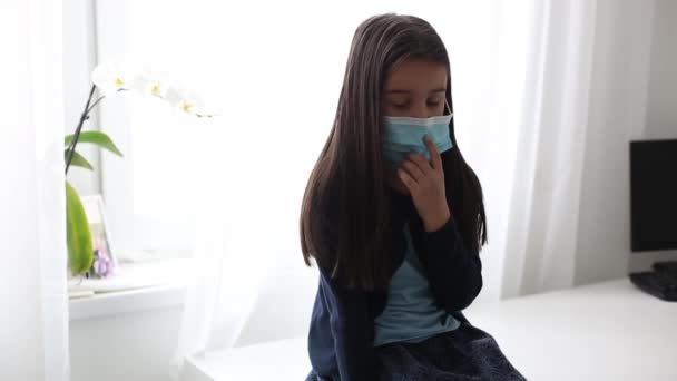 Petite fille malade portant un masque médical contre le virus gros plan regardant la caméra. Épidémie intérieure, auto-isolement, quarantaine à domicile, pandémie, coronavirus — Video