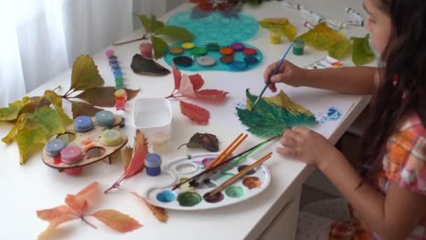 Meisje schilderen op herfst gele bladeren met gouache, kinderen kunst, kinderen creativiteit, herfst kunst. — Stockvideo