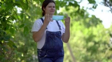 Hamile kadın tıbbi maske takıyor. Bebek bekleyen çok renkli saçlı bir kadın koruyucu maske kullanıyor. Salgın sırasında korunma teması.