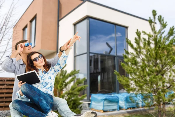 Couple heureux avec leur nouvelle maison en arrière-plan et souriant — Photo