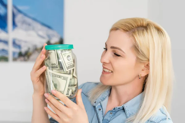 Mujer feliz en jersey gris banco de espera con dinero en efectivo en dólares, mirando a la cámara, aislado sobre fondo beige — Foto de Stock