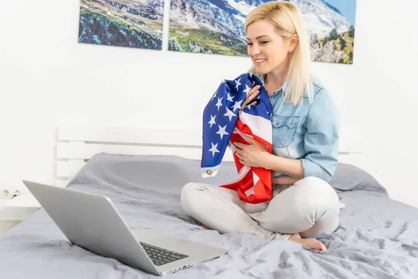 Jonge vrouw met USA vlag met behulp van een laptop computer, onafhankelijkheidsdag online — Stockfoto