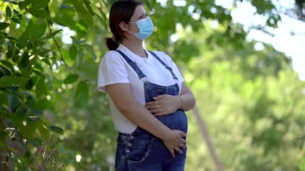 Portret van jonge zwangere vrouw in medische steriele masker loopt op het bos, verwijder beschermende gezichtsmasker glimlach diep voelt gelukkig en gezond. Quarantaine einde, covid-19 verslagen concept — Stockvideo