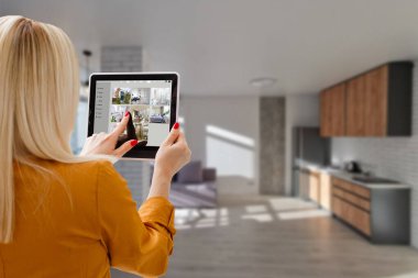 Modern bir evde ev yapımı 3D bir ev otomasyon kontrol istasyonuna sahip bir kadın.