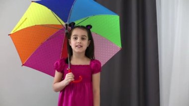 Renkli şemsiyeli küçük bir kız bir mısra okuyor.