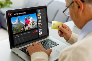 Adam gelecek seyahati planlamak için bilgi topluyor, web sitesinde internet üzerinden rezervasyon yaptırıyor, internetten bir geziyle ilgili video seyrediyor.