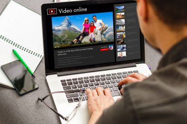 Adam gelecek seyahati planlamak için bilgi topluyor, web sitesinde internet üzerinden rezervasyon yaptırıyor, internetten bir geziyle ilgili video seyrediyor.