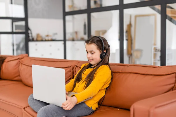 Kind online. Ein kleines Mädchen kommuniziert mit einem Laptop-Videochat, während es zu Hause am Laptop sitzt — Stockfoto