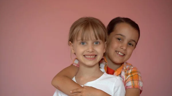 Two happy girls hugging each other isolated on pink background — Stock Photo, Image