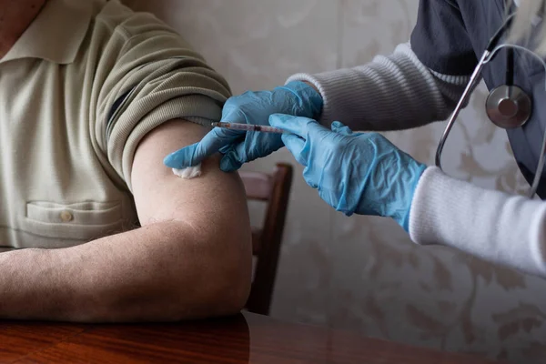 Läkare som förbereder vaccinering av äldre patienter genom att hålla sprutan i hemmet - begreppet hälsokontroll i hemmet av äldre under coronavirus covid-19 pandemi — Stockfoto