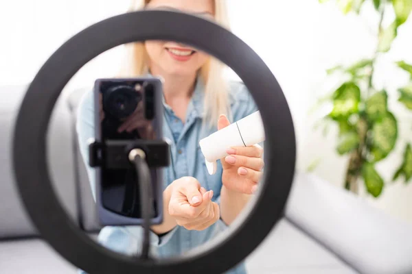Bloggare kvinna inspelning video på smartphone och tända sig med ringlampa vid bordet i ljusrummet — Stockfoto