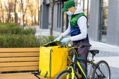 Eve servis için sarı termo çantalı bir teslimatçı. Eve yakın bir yerde. Kopyalamak için boş bir yer var.