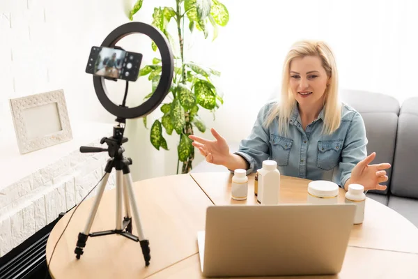 Blogueuse femme enregistrement vidéo sur smartphone et s'allumer avec lampe annulaire à la table dans la salle de lumière — Photo
