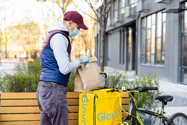 KIEW, UKRAINE - 28. April 2021: Glovo-Lieferjunge mit berühmtem gelben Kasten und Fahrrad auf der Straße. Lieferservice-Mitarbeiter auf dem Fahrrad — Stockfoto