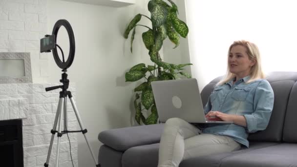 Μια γυναίκα μπλόγκερ που βιντεοσκοπεί σε τρίποδο. Influencer κυρία live streaming κριτική στο στούντιο στο σπίτι. — Αρχείο Βίντεο