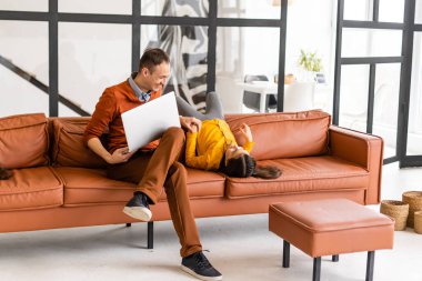 Baba ve kızı evde dizüstü bilgisayar kullanıyor.