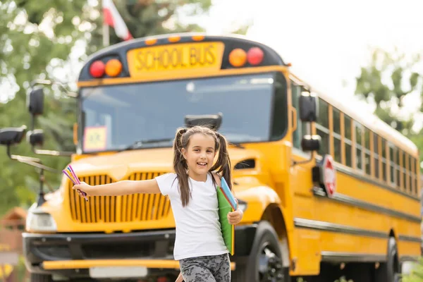 Schattig meisje met een rugzak staan in de buurt van bus naar school poseren camera pensive close-up — Stockfoto