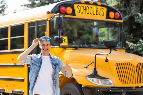 Un profesor varón feliz cerca del autobús escolar — Foto de Stock