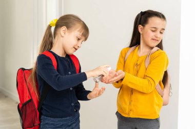 Okula geri dönmek, okul çocukları hijyen, koronavirüs sonrası güvenlik önlemleri. Liseli kız okula gidiyor ve ellerini dezenfektanla yıkıyor.