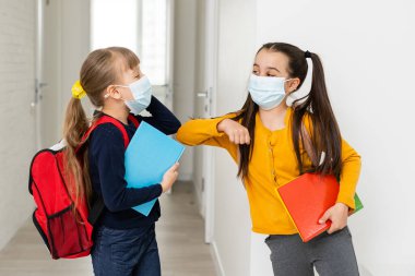 Sırt çantalı koruyucu maskeli iki öğrenci arkadaş. Okul konseptinde gün