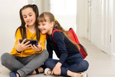 Ders aralarında akıllı telefondan oynayan iki modern okul arkadaşı.