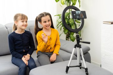 Fotoğrafı kapatın. İki küçük kız selfie çekin, konuşun, konuşun, konuşun.