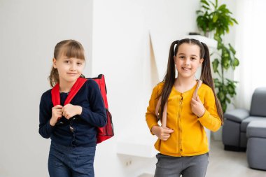 Konuşan ve sırlarını paylaşan iki küçük kız öğrenci. Eğitim, moda, arkadaşlık kavramı.