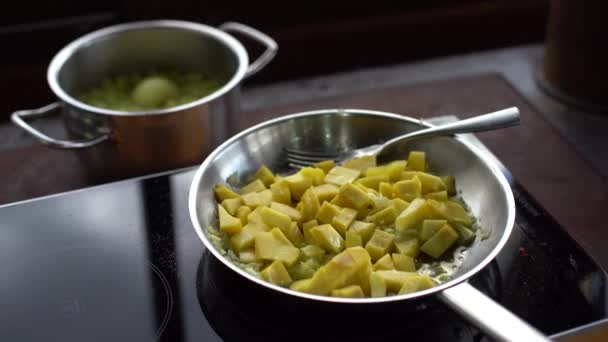 Potatis, som steks i en stekpanna, blandas med sked. Skär potatis stekt i olja. Närbild — Stockvideo