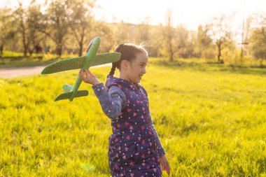 Hızlı koşan ve uçak oyuncağı tutan kız.