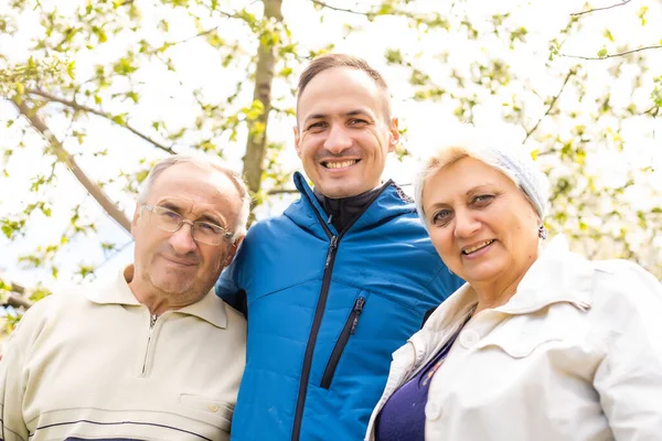 Erwachsener Sohn mit seinen betagten Eltern im Freien in einer natürlichen Umgebung. — Stockfoto