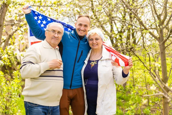 Familie vor der Haustür am 4. Juli mit Fahnen, lächelnd — Stockfoto