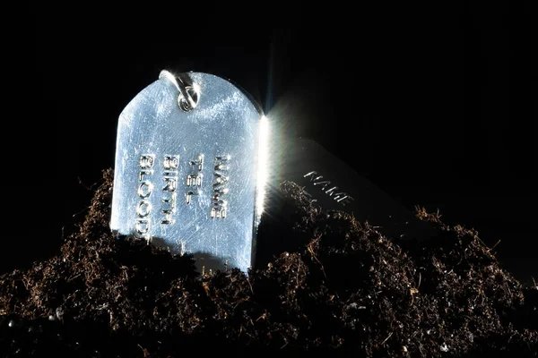 Silvery military token lies on a pile of soil — Stock Photo, Image