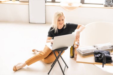 Genç ve güzel bir kadın evde dizüstü bilgisayar kullanıyor.