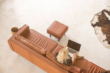 Genç ve güzel bir kadın evde dizüstü bilgisayar kullanıyor.